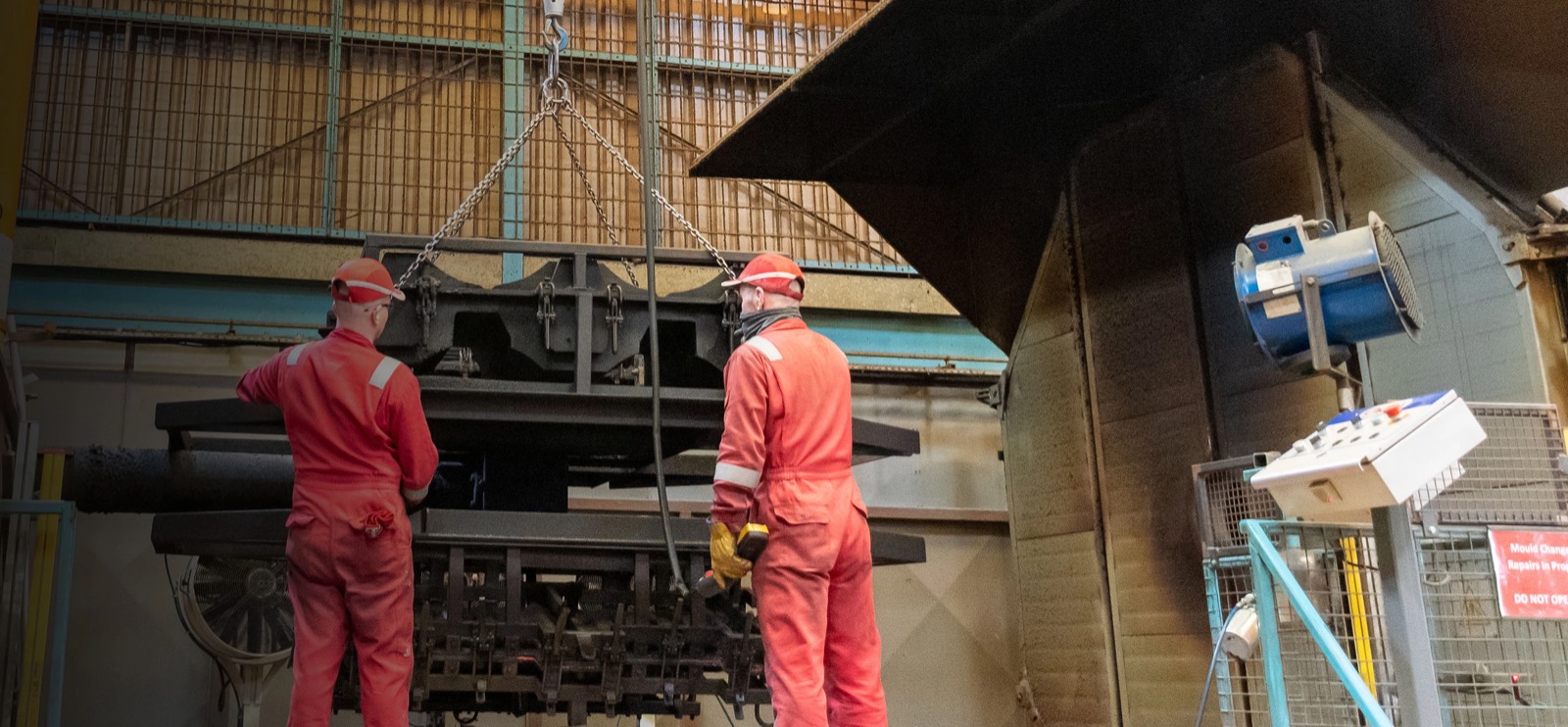 Two technicians in red overalls testing a tool